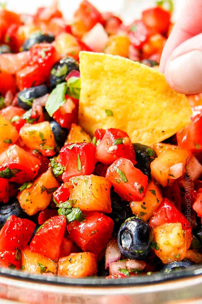 up close dipping a tortilla chip into strawberry salsa