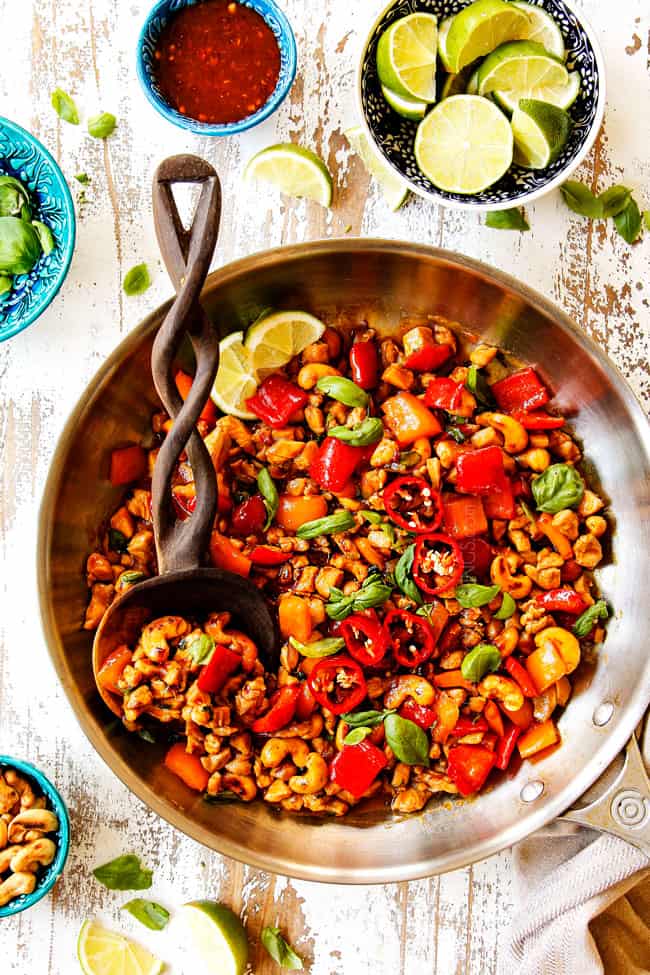 showing how to make Basil Chicken by stir frying chicken and bell peppers together in a stainless steel skillet
