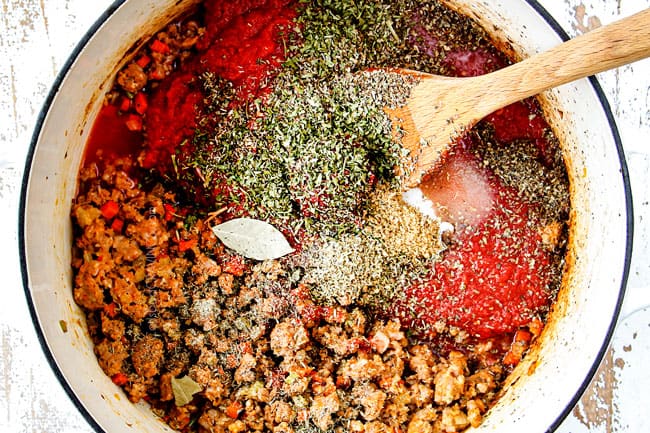 showing how to make zucchini lasagna by making homemade Bolognese by adding Italian sausage, crushed tomatoes, basil, parsley to a white Duch oven