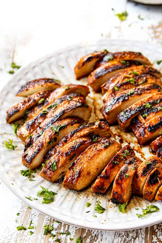 two marinated balsamic chicken breasts on a plate garnished by parsley
