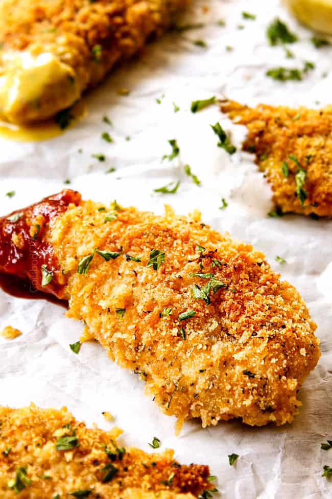 up close of a breaded Parmesan crusted chicken tender dipped in sauce