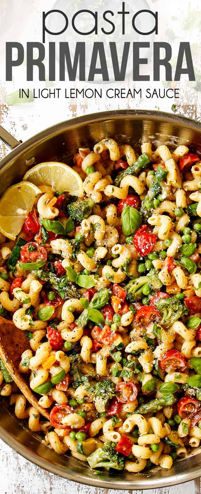 top view of pasta primavera recipe in a stainless steal skillet with broccoli, squash, zucchini, asparagus, bell peppers, tomatoes and peas