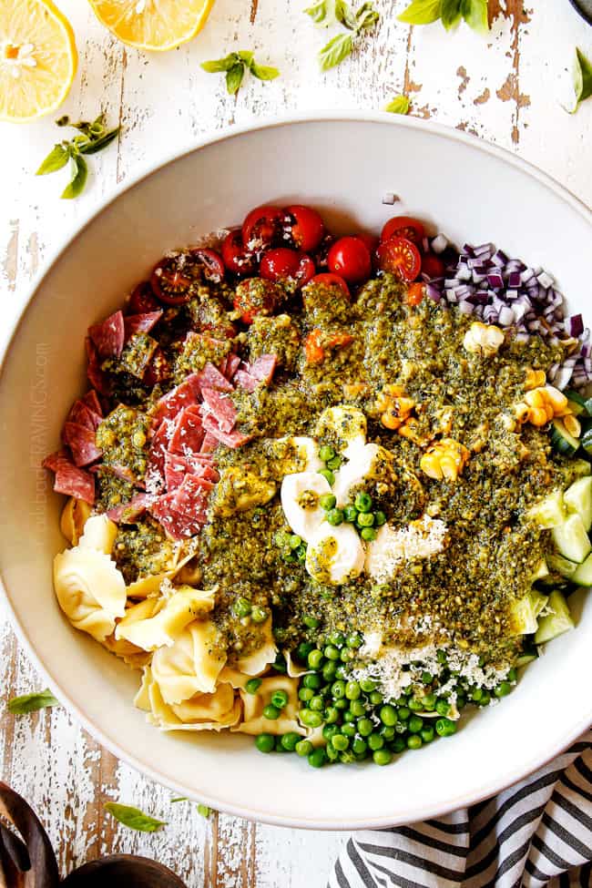top view showing how to make pesto pasta salad by adding pesto dressing to the salad