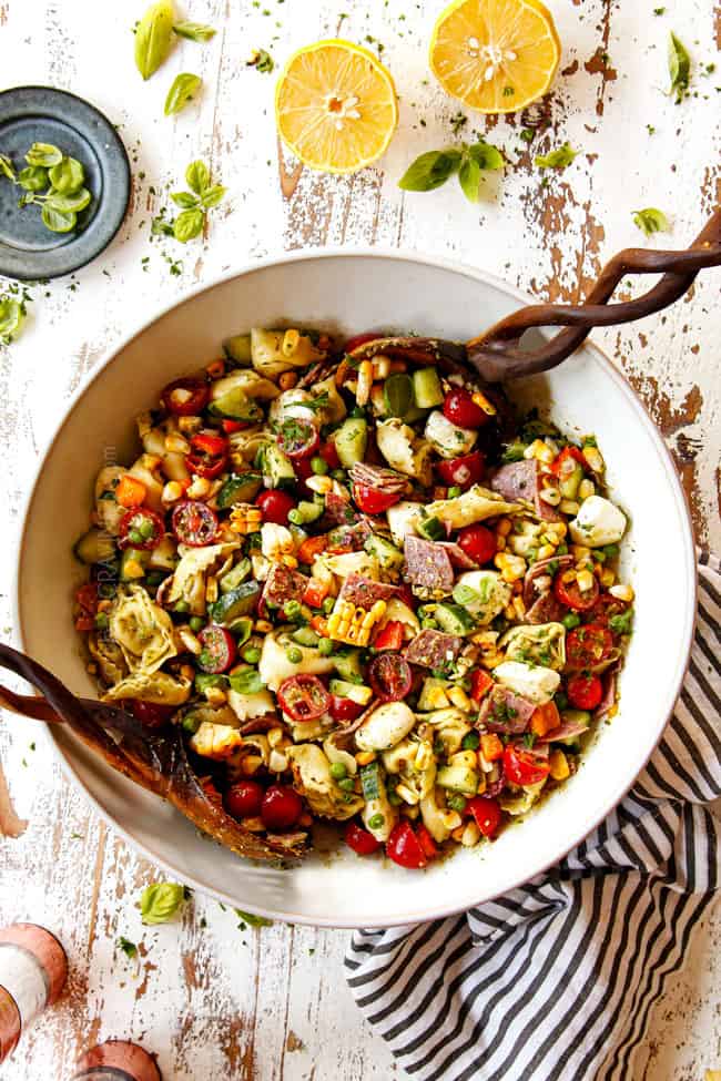 top view of pesto pasta salad with peas, mozzarella, and tomatoes in a white bowl