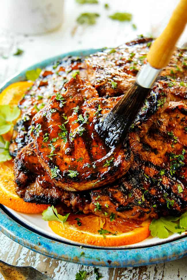 brushing reserved pork chop marinade on grilled pork chops