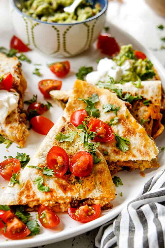 up close of breakfast quesadillas on a white platter garnished with tomatoes and cilantro