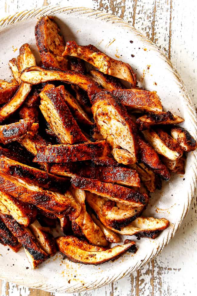 top view of chicken seasoned with homemade fajita seasoning sliced in a tan bowl