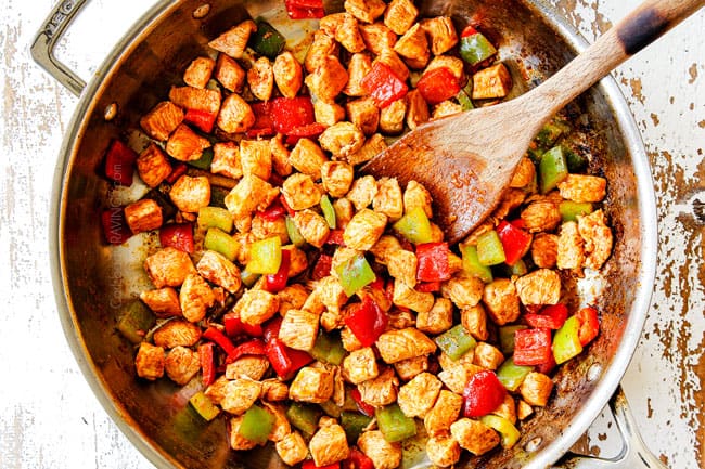 showing how to make mango chicken recipe by stir frying bell peppers with the chicken