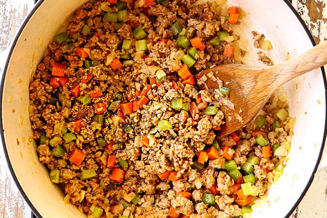 top view showing how to make corn chowder by sautรฉing carrots, celery and onions in a white Dutch oven