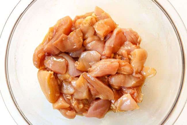 showing how to make pad see ew recipe by marinating chicken with soy sauce and sesame oil in a glass bowl