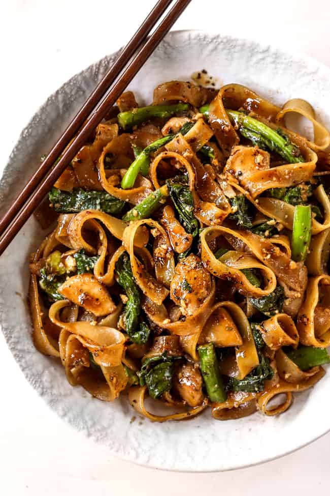 top view of pad see ew noodles in a white bowl with wooden chopsticks