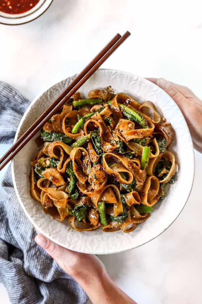 top view of two hand holding pad see ew in a white bowl