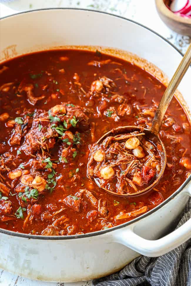 pozole recipe in a white Dutch oven with a ladle scooping the soup