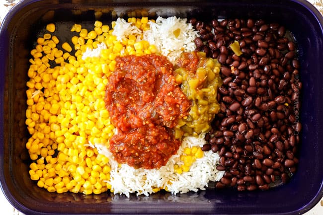 showing how to make baked salsa chicken recipe by adding corn, beans, rice, salsa and green chilies to a blue 9x13 baking dish
