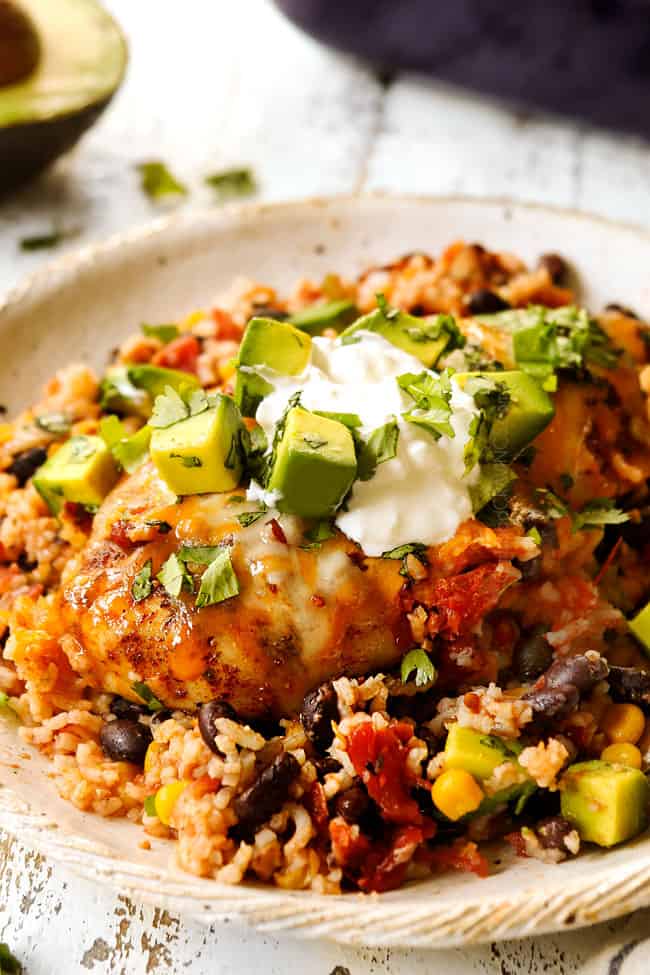 showing how to serve salsa chicken recipe by adding to a plate and topping with sour cream, cilantro and avocados