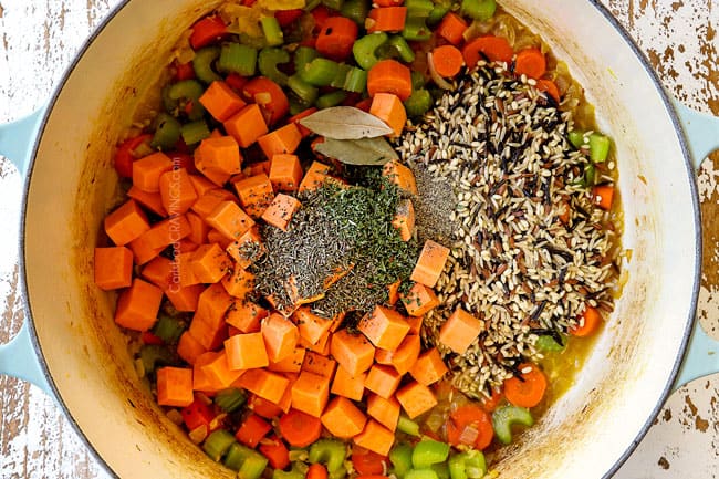 showing how to make leftover turkey rice soup by adding wild rice, sweet potatoes and Italian seasonings to a white Dutch oven