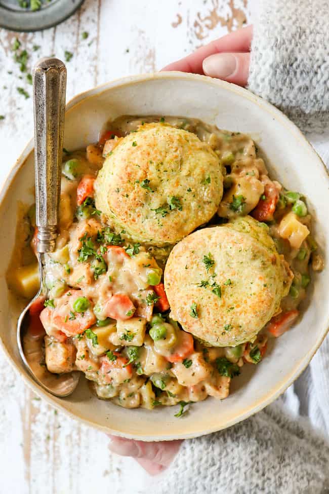 two hands holding homemade chicken pot pie with biscuits