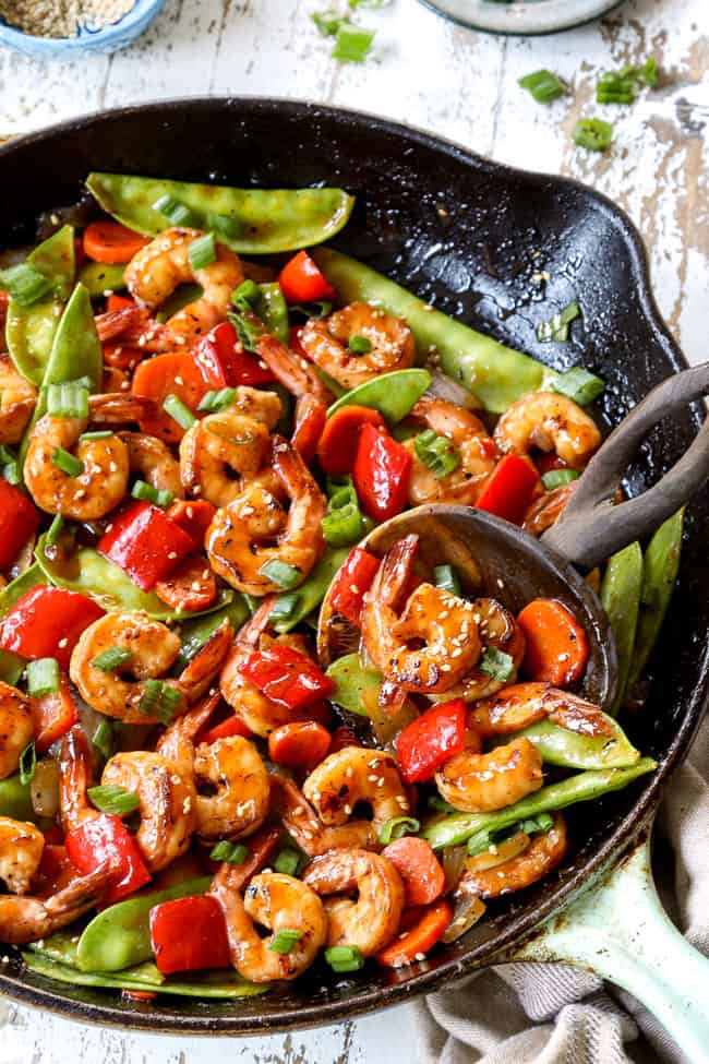 showing how to make shrimp stir fry by combining shrimp and vegetables in a skillet