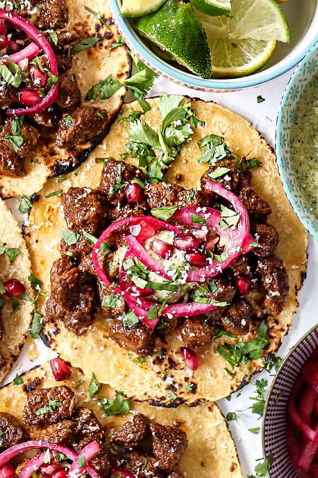 top up close view of a steak taco laid flat garnished with cilantro and pickled red onions