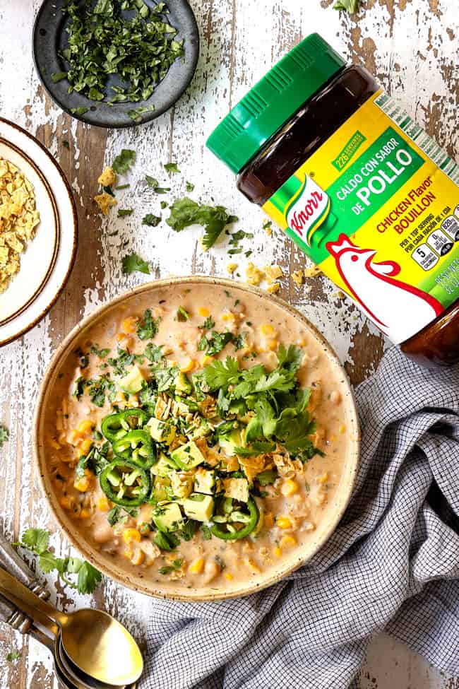 top view of creamy white chicken chili in a bowl with avocados, cilantro and jalapenos