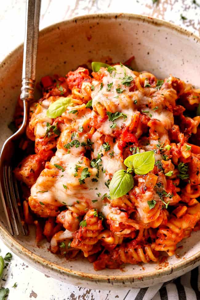 a bowl of chicken Parmesan pasta garnished with parsley and fresh basil