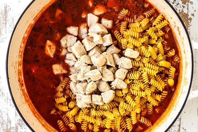showing how to make Chicken Parmesan Pasta by adding chicken and pasta to pot