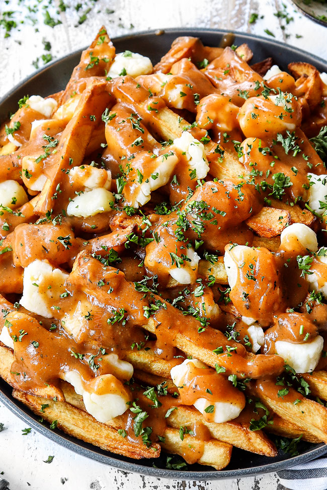up close of poutine with gravy and cheese curds on a plate showing how crispy the French fries are
