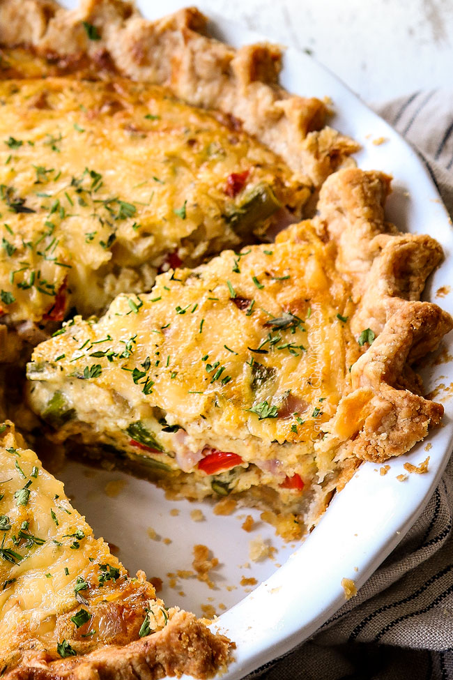 showing how to make ham and cheese quiche by garnishing slices with fresh parsley