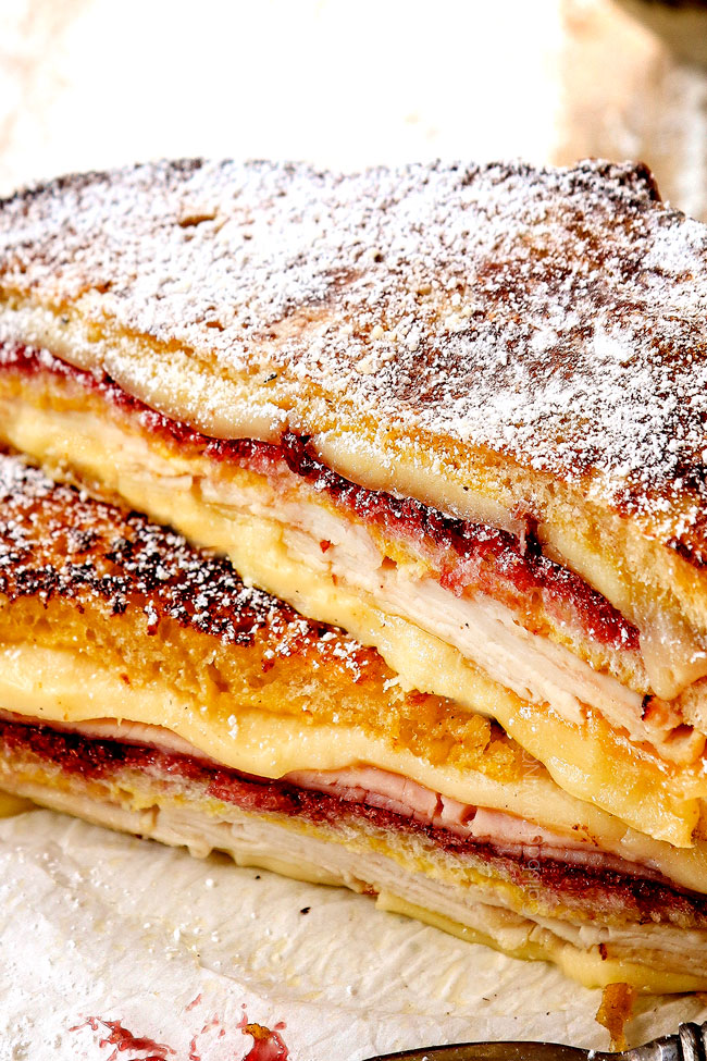 showing how to make Monte Cristo recipe by dusting with powdered sugar and serving with raspberry jam