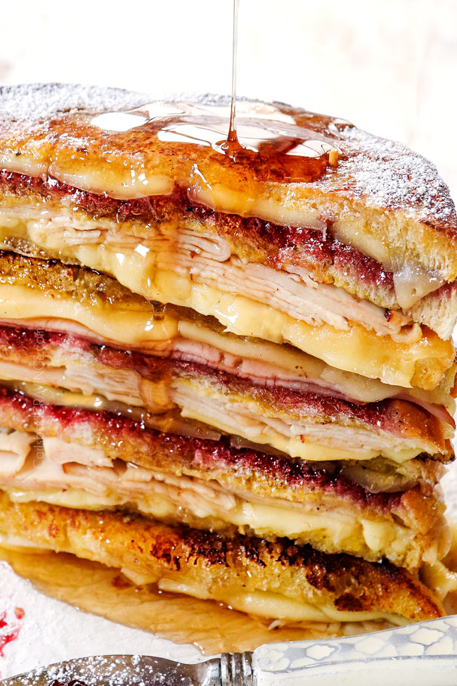 showing how to make Monte Cristo sandwich recipe by drizzling a stack of Monte Cristos with syrup