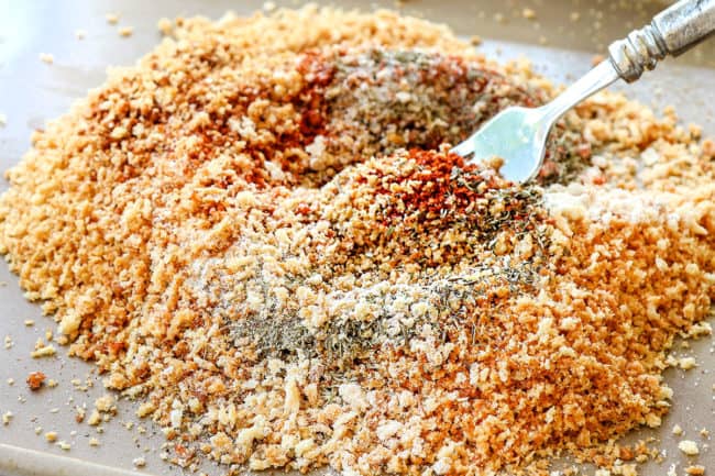 showing how to make chicken nuggets by stirring spices into toasted panko on a baking sheet