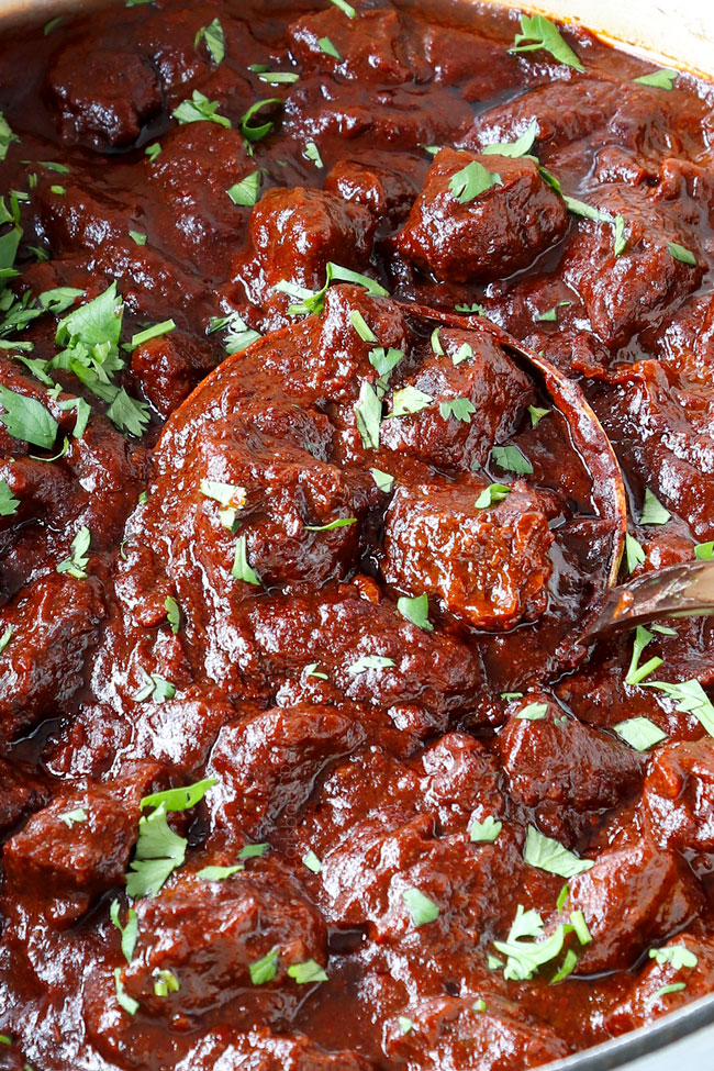 showing how tender the Chile Colorado is with a big ladleful of stew