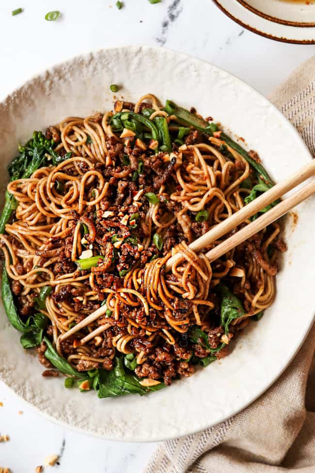 top view of Dan Dan Noodles in a white bowl garnished with green oions