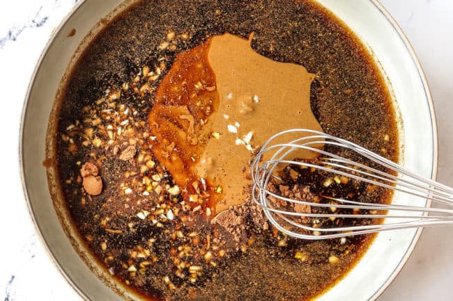 showing how to make Dan Dan Noodles recipe by whisking ingredients together for Dan Dan Sauce