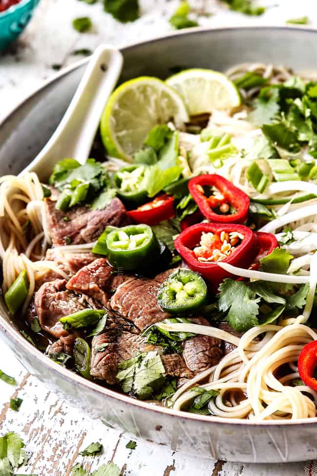 pho recipe with thinly sliced beef garnished with chili peppers, bean sprouts and cilantro