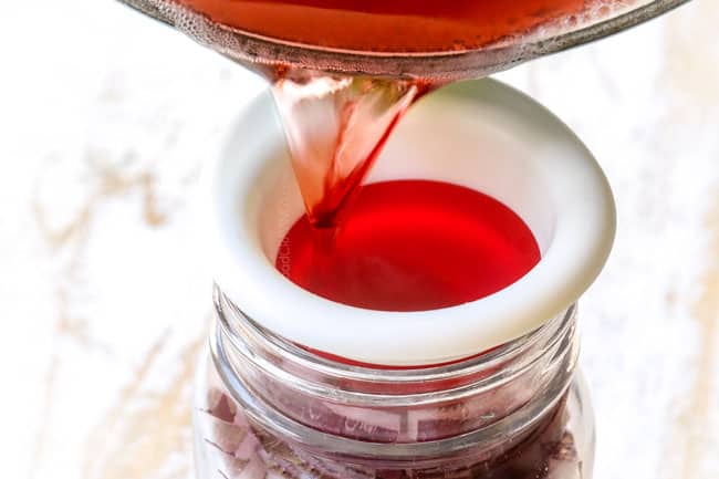 showing how to pickle red onions by pouring brining liquid into jar with onions through a funnel