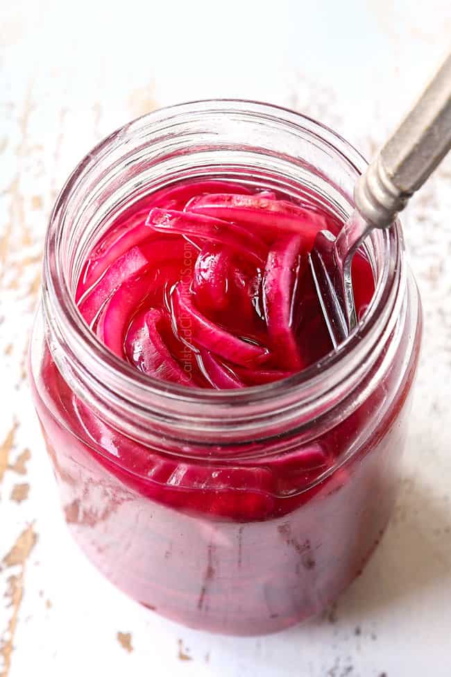 side view of picking up pickled red onions with a fork