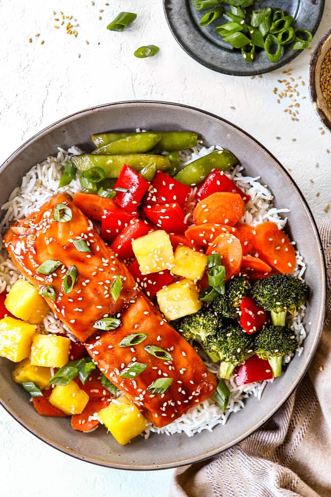 top view of a bowl of baked teriyaki salmon with broccoli, carrots, bell peppers and pineapple