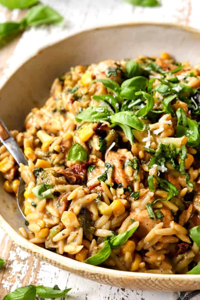 basil chicken in a an bowl with a spoon scooping up chicken