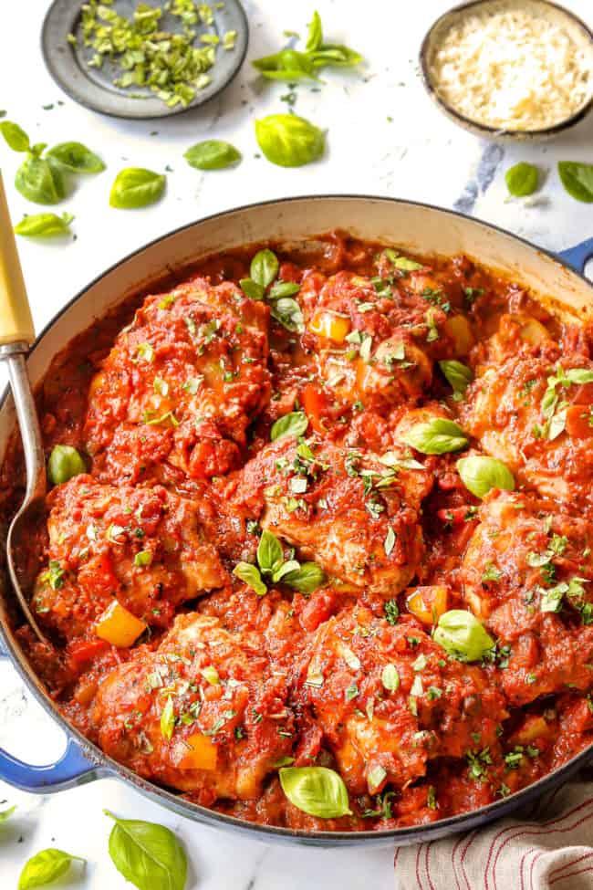 chicken cacciatore in a blue pot with a serving spoon scooping up chicken