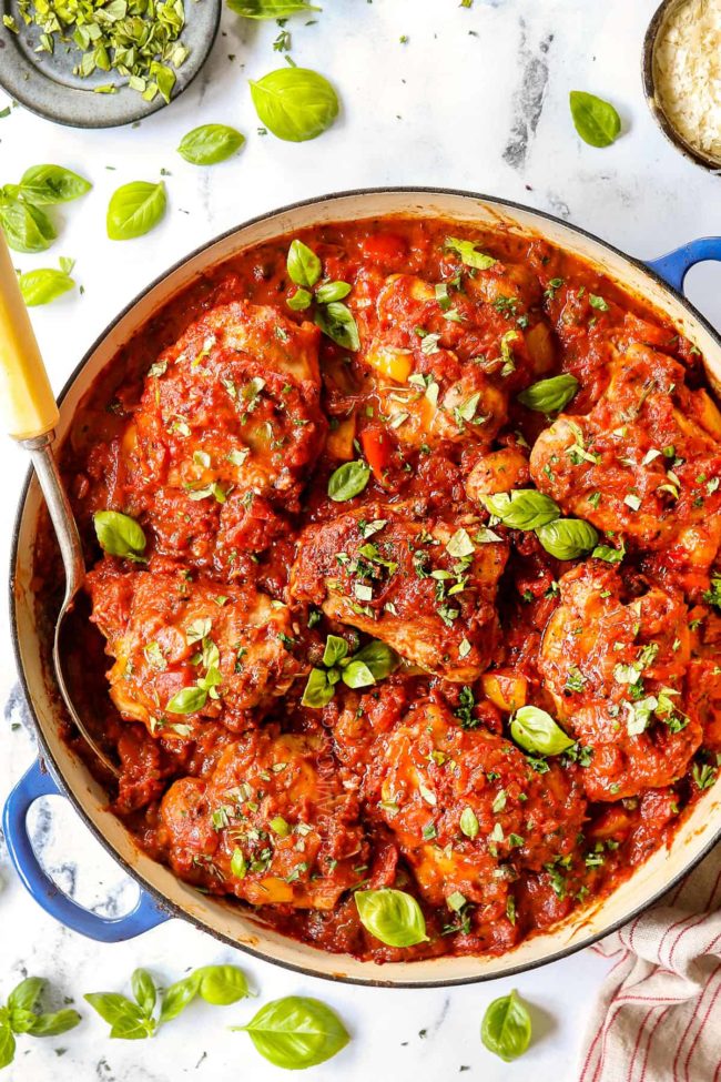 top view of chicken cacciatore recipe in a blue braiser with a serving spoon