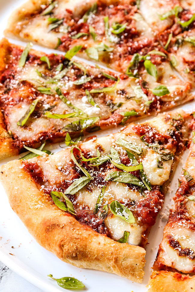 showing what's on a margherita pizza by adding pizza sauce, fresh mozzarella, fresh basil and Parmesan to pizza