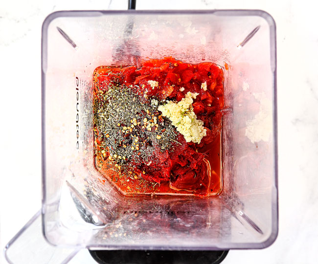 showing how to make margherita pizza sauce by adding ingredients to a blender