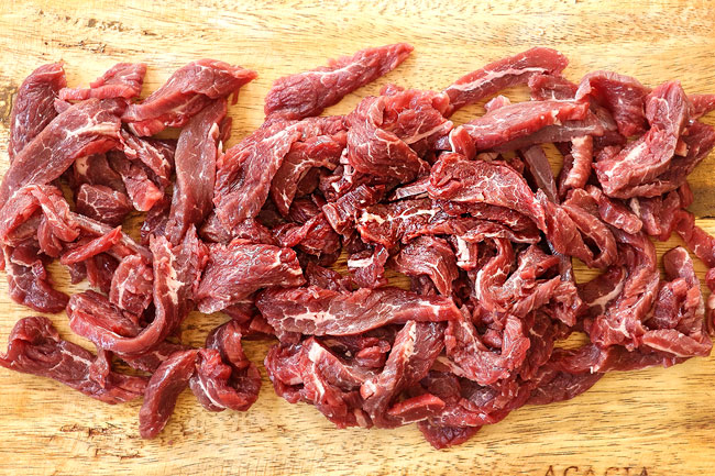 showing how to make beef teriyaki recipe by slicing beef on a cutting board