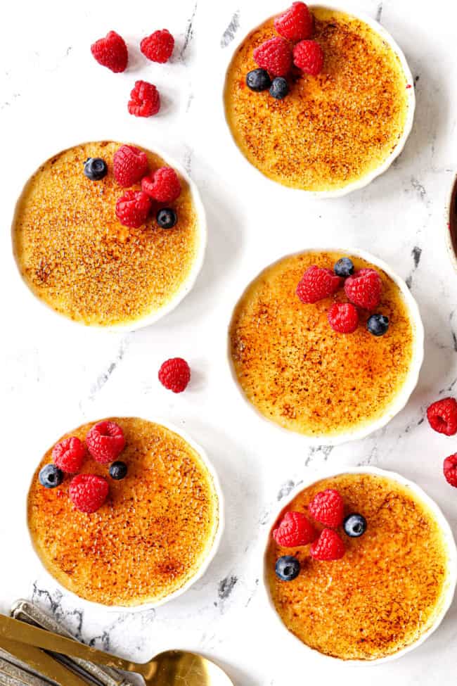showing how to garnish creme brรปlรฉe recipe with top view of creme brulee with raspberries and blueberries