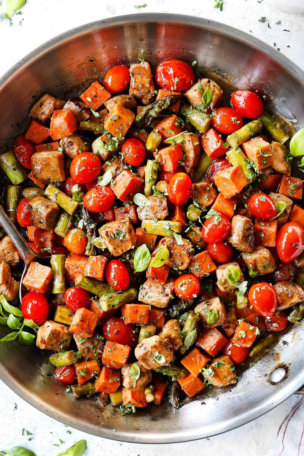 showing how to make balsamic chicken recipe by combining chicken, tomatoes, asparagus in a skillet