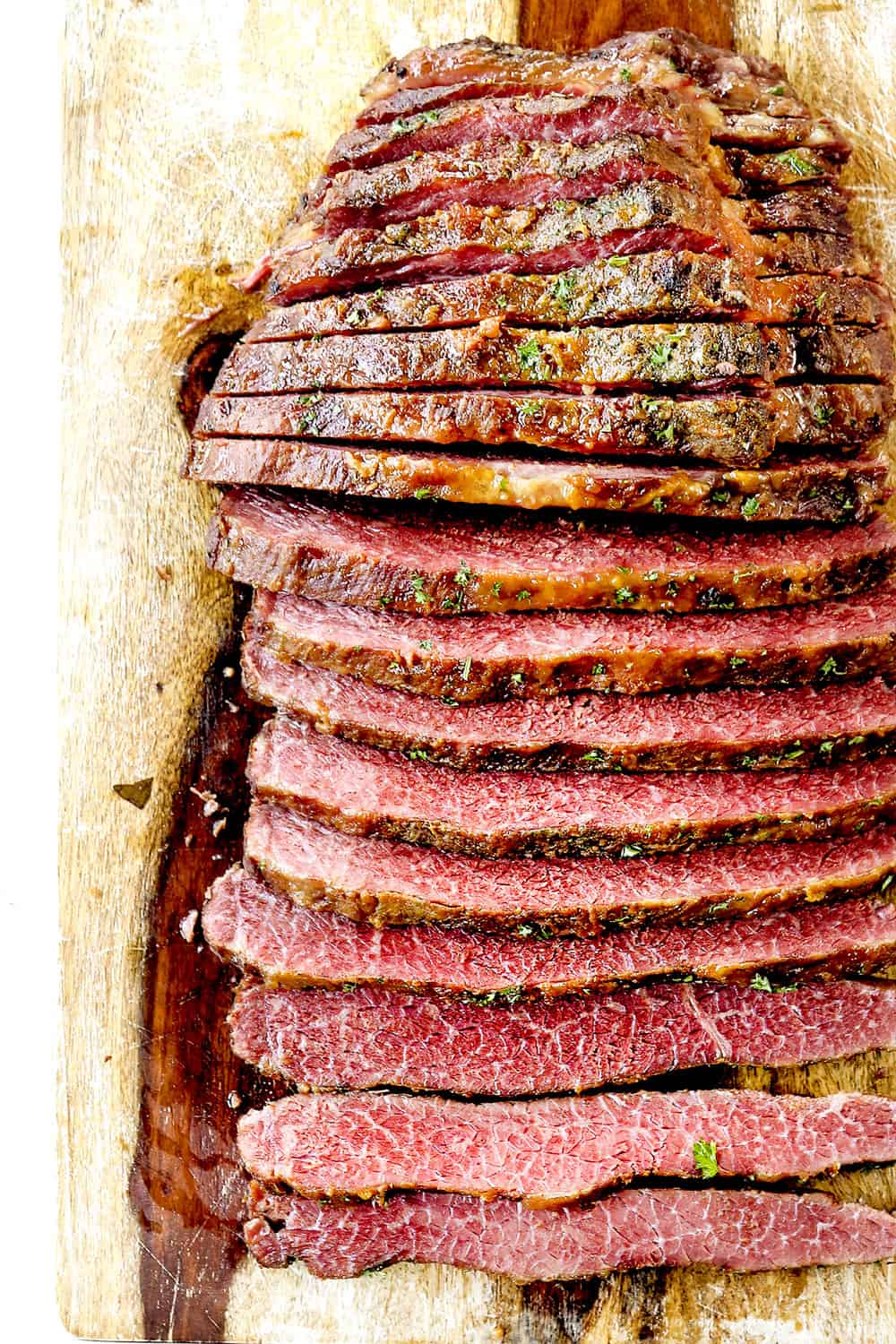 showing how to make corned beef for Reuben Sandwich by slicing corned beef brisket across the grain on a wood cutting board