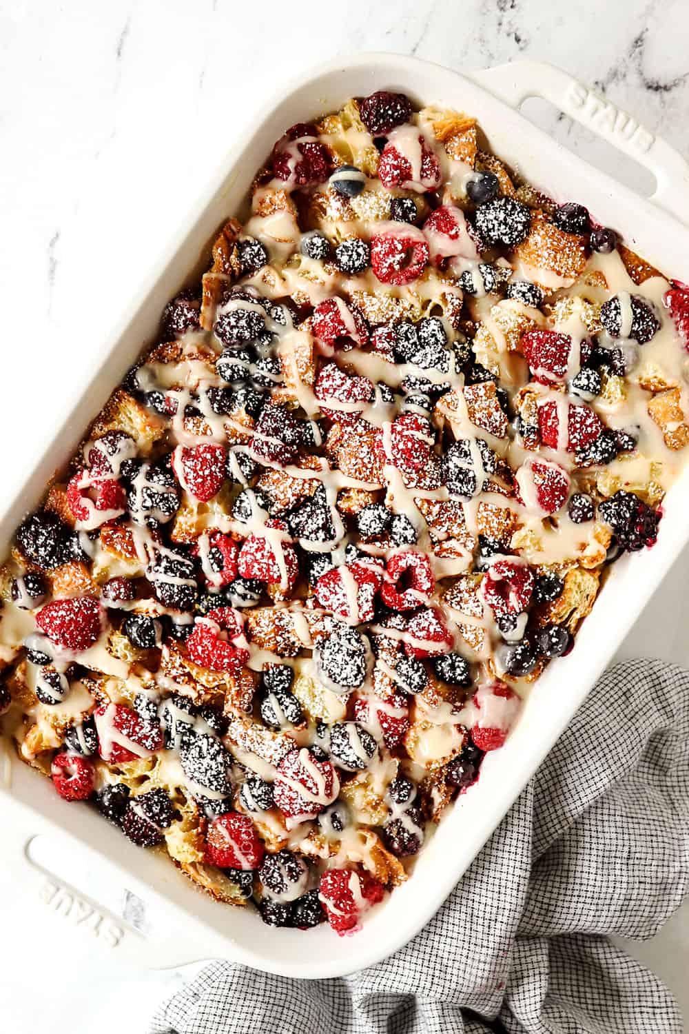 top view of croissant breakfast casserole with berries in a white casserole dish