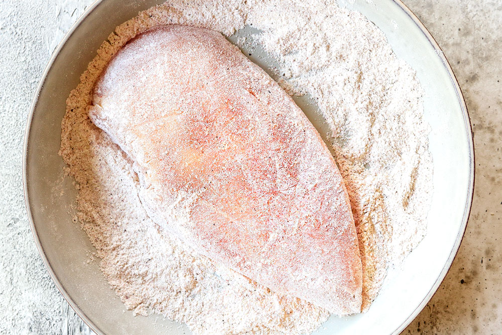 showing how to make Chicken mushroom recipe by dredging chicken breasts in flour