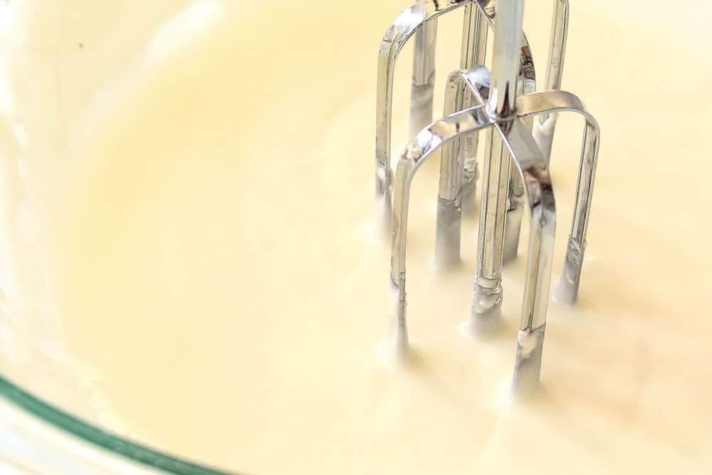 showing how to make lemon glaze for cake by beating sugar, powdered sugar and lemon juice together